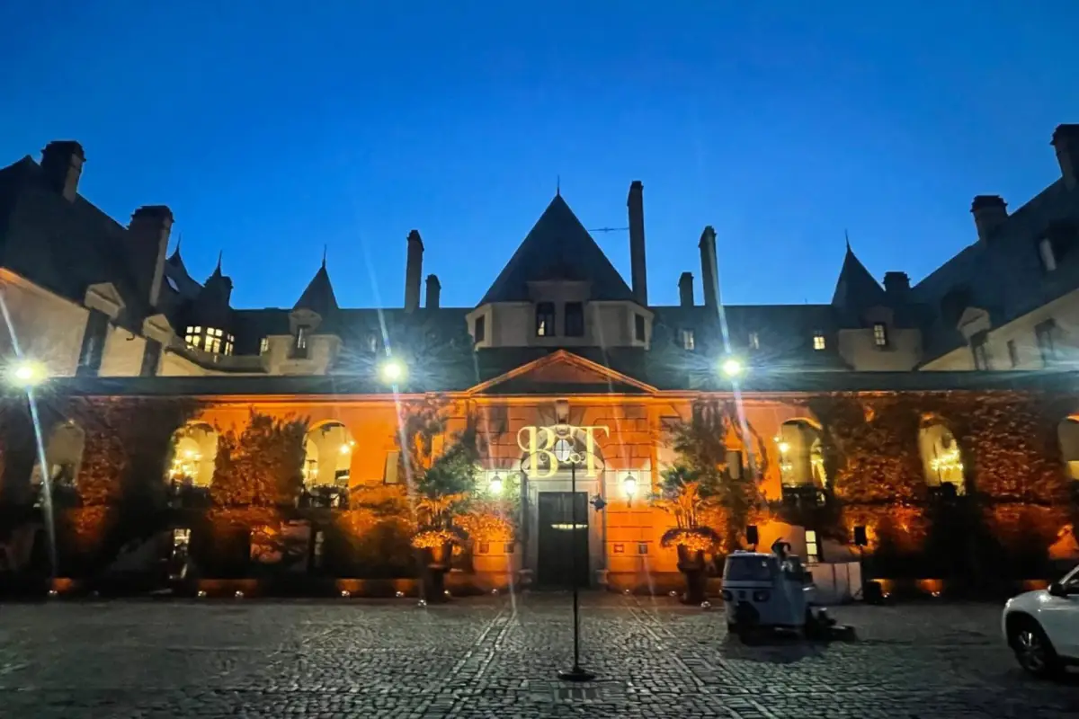 Exterior view of a beautifully lit castle-like venue with warm amber lighting highlighting architectural details against a twilight sky.