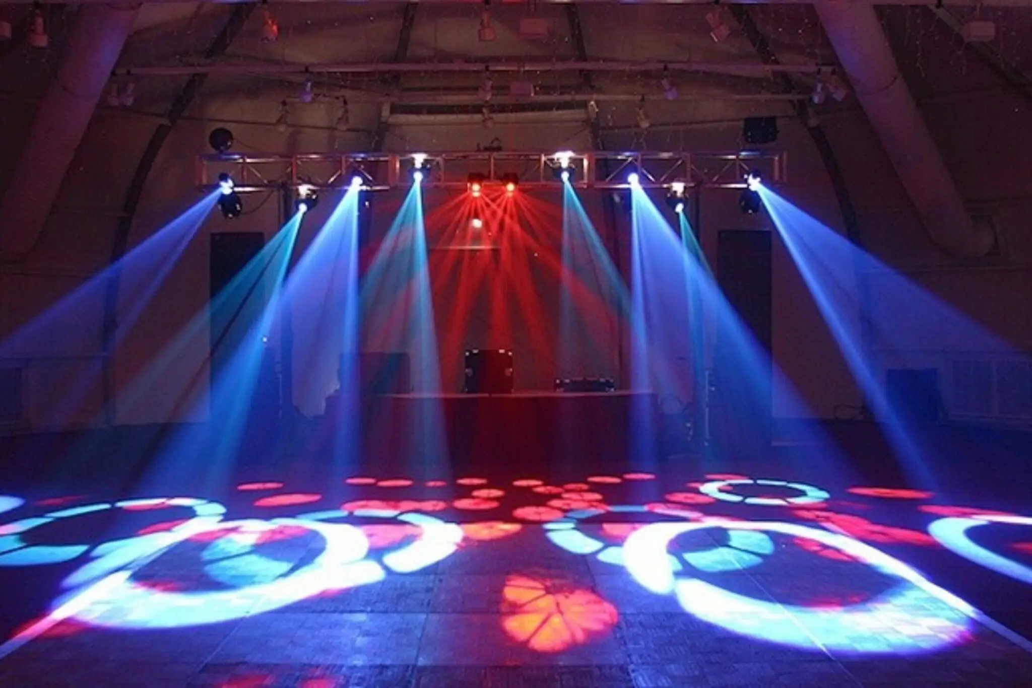 Elegant indoor lighting display featuring colorful spotlights on a dance floor, creating a vibrant atmosphere.